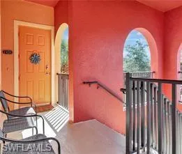 Exterior entry with a paneled door, arched openings, a dark metal railing, and a handrail