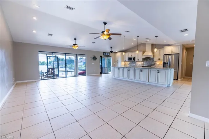 Stainless steel appliances, lofted ceiling, ceiling fan, and dark stone counters