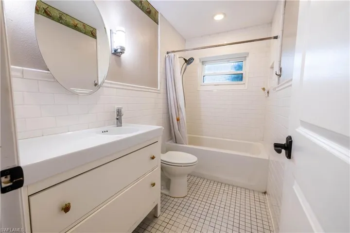 Full bathroom featuring vanity, shower / bath combination with curtain, tile patterned flooring, tile walls, and toilet
