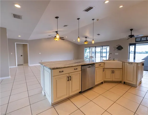 Kitchen featuring dishwasher, an island with sink, and ceiling fan