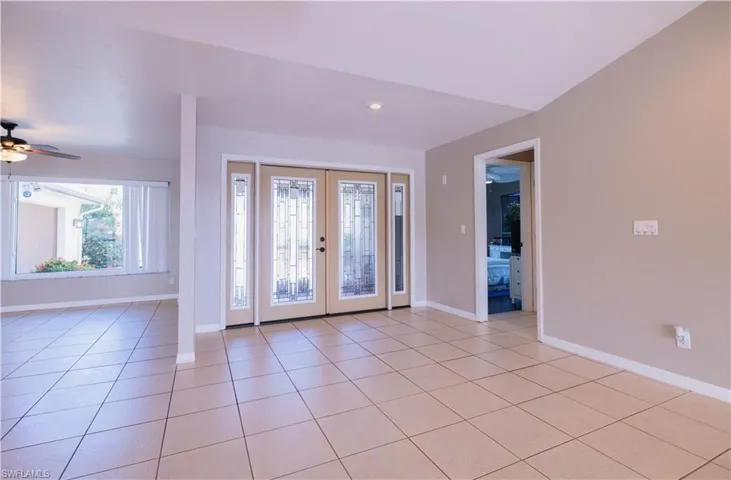 Tiled entryway with ceiling fan and french doors