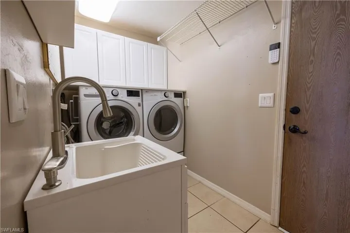 Laundry room with cabinets, washer and clothes dryer, and light tile patterned flooring