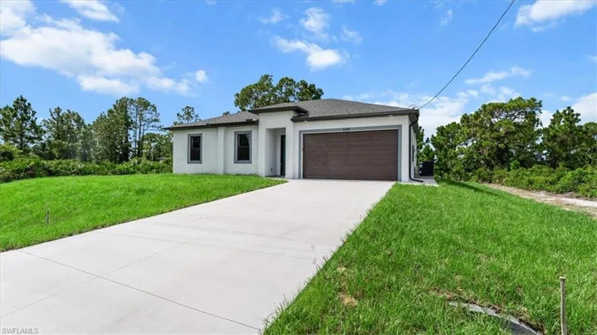 Prairie-style house with stucco siding, concrete driveway, a front yard, and a garage