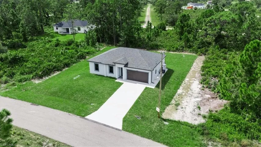 View of subject property featuring a tree filled landscape