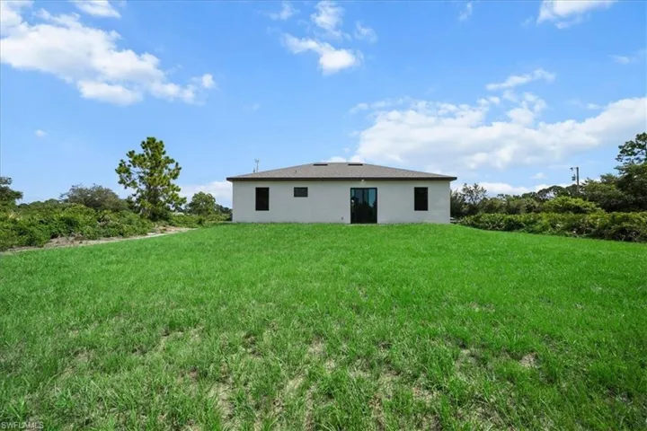 Rear view of house featuring a lawn and stucco siding