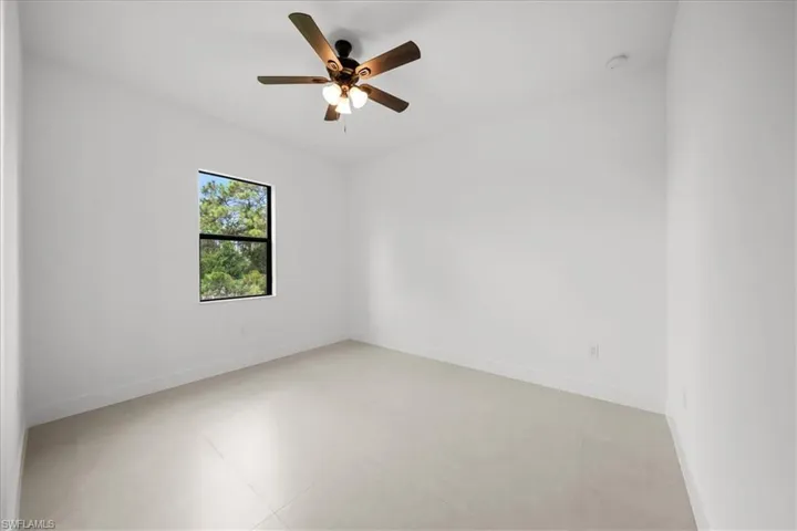 Spare room featuring a ceiling fan and baseboards