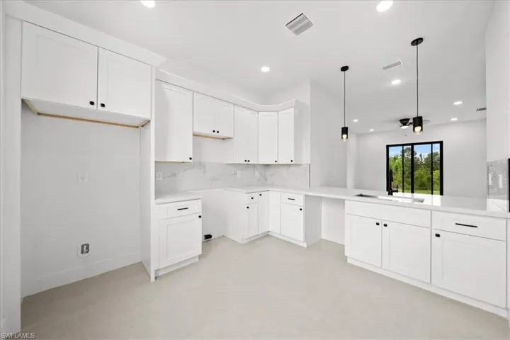 Kitchen with white cabinetry, decorative backsplash, recessed lighting, hanging light fixtures, and concrete floors