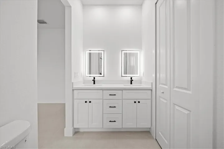 Full bathroom with light tile patterned floors and double vanity