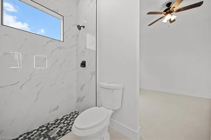 Full bathroom with a marble finish shower and a ceiling fan