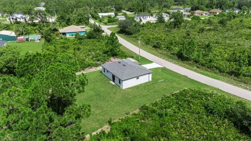 Aerial view of property and surrounding area featuring a tree filled landscape
