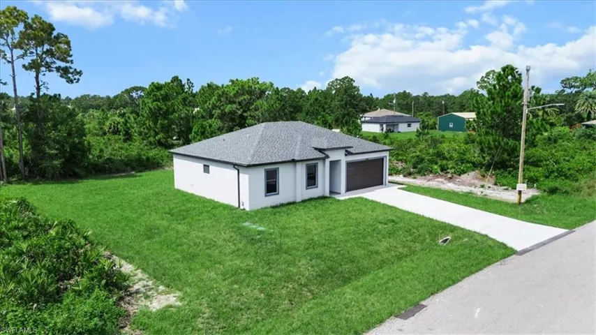 View of front of home with concrete driveway, a shingled roof, a front yard, an attached garage, and stucco siding