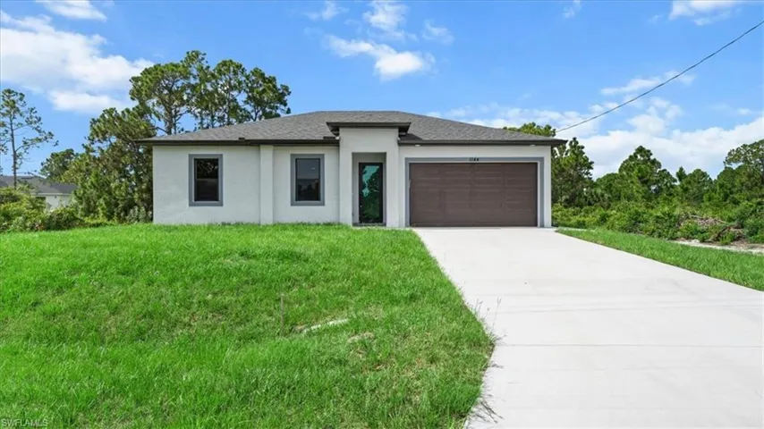 Prairie-style home with driveway, stucco siding, a garage, and a front lawn