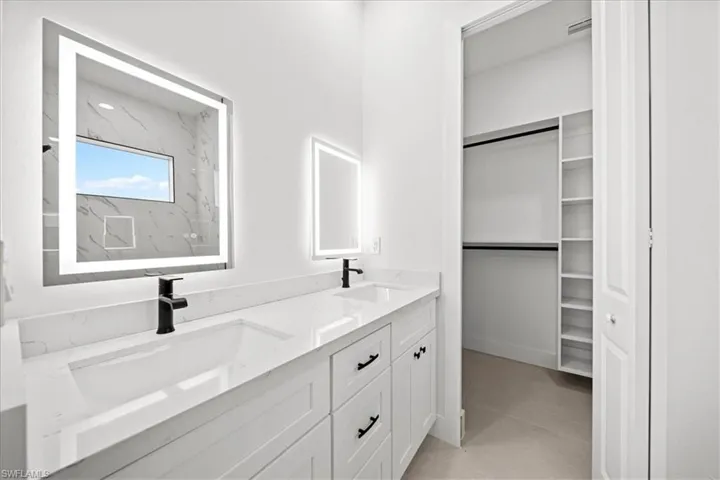Full bathroom with double vanity, a spacious closet, and light tile patterned floors
