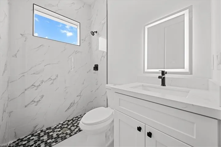 Full bathroom featuring vanity and a marble finish shower