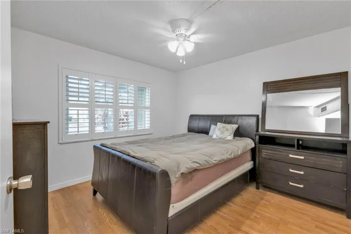 Bedroom with light wood finished floors, baseboards, ceiling fan, and a textured ceiling