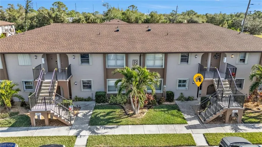 Multi unit property featuring stairway, stucco siding, a shingled roof, and a front yard