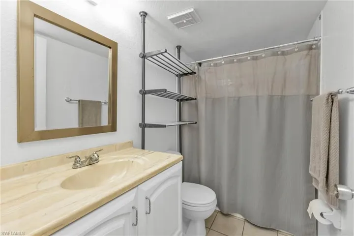 Bathroom with tile patterned floors, toilet, vanity, and curtained shower
