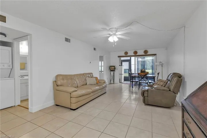 Living area featuring estacked washer and dryer, ceiling fan, and light tile patterned flooring