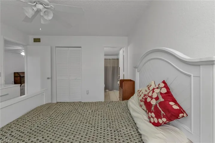 Tiled bedroom featuring ensuite bath, a ceiling fan, a closet, and a textured ceiling