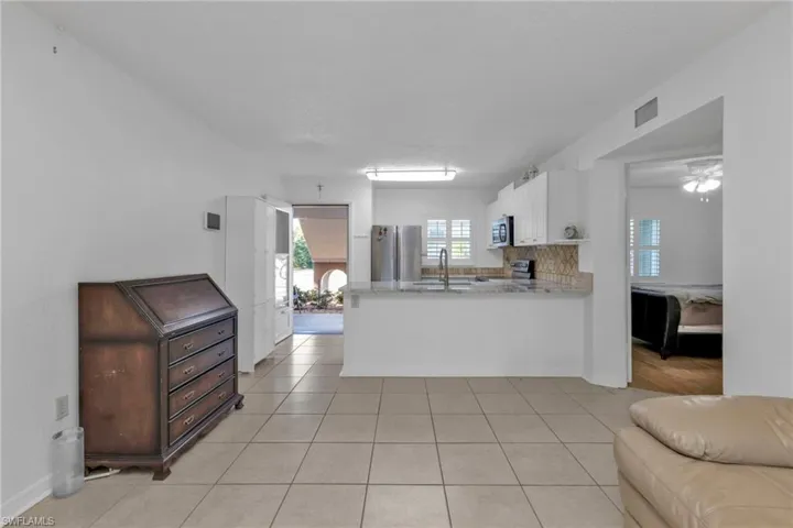 Kitchen featuring a sink, open floor plan, appliances with stainless steel finishes, a peninsula, and white cabinets