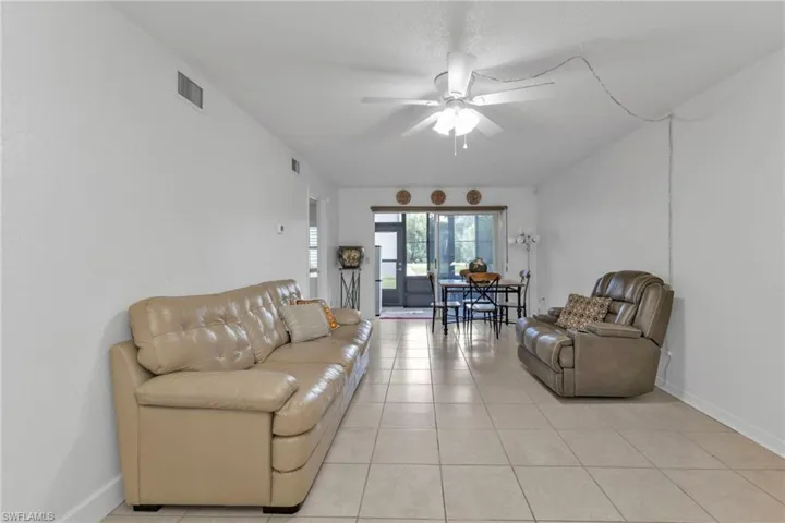 Living area featuring ceiling fan, light tile patterned floors, and baseboards