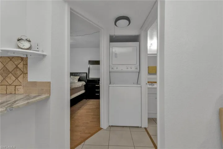 Bathroom with stacked washer and clothes dryer, tasteful backsplash, tile patterned floors, and a textured wall