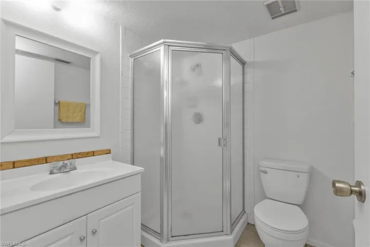 Full bath featuring a shower stall, toilet, and vanity