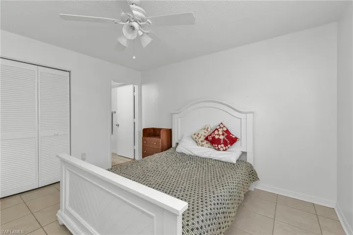 Bedroom with light tile patterned flooring, baseboards, a closet, and ceiling fan