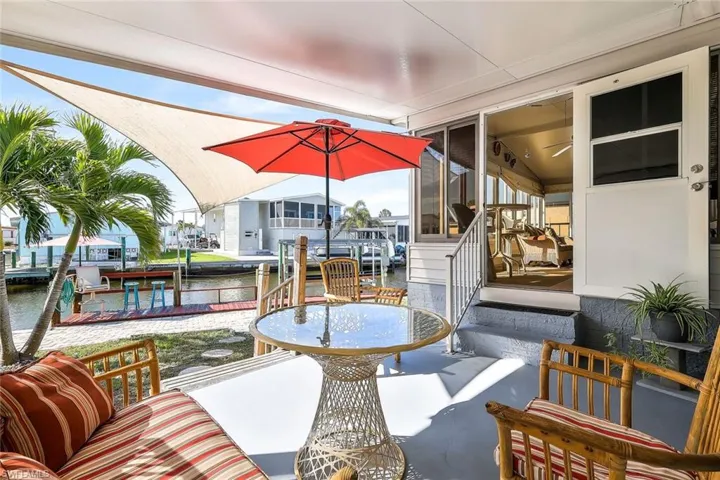 View of patio featuring a sunroom, a water view, and a boat dock