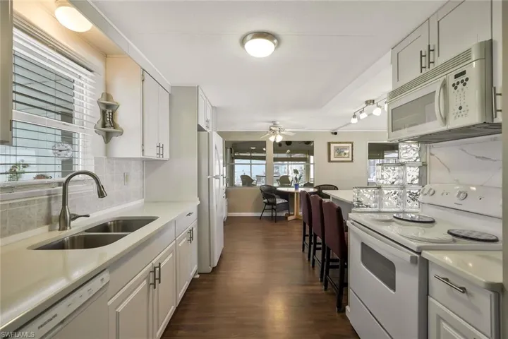 Kitchen featuring light countertops, white appliances, a ceiling fan, a sink, and backsplash