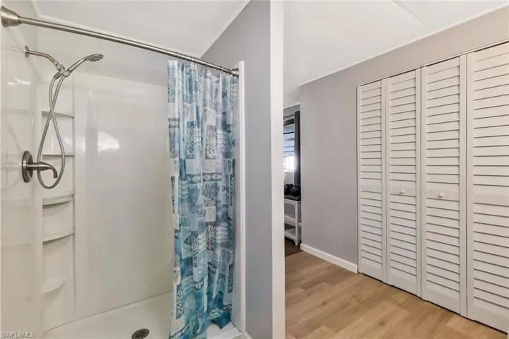 Full bath with wood finished floors and a stall shower