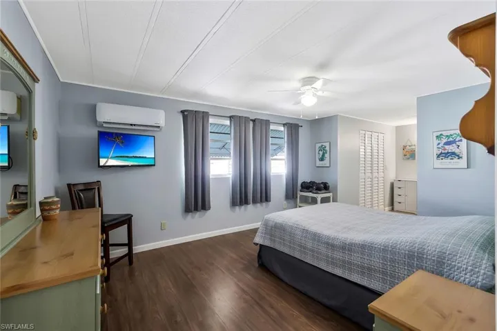 Bedroom featuring baseboards, a wall mounted AC, ceiling fan, and wood finished floors