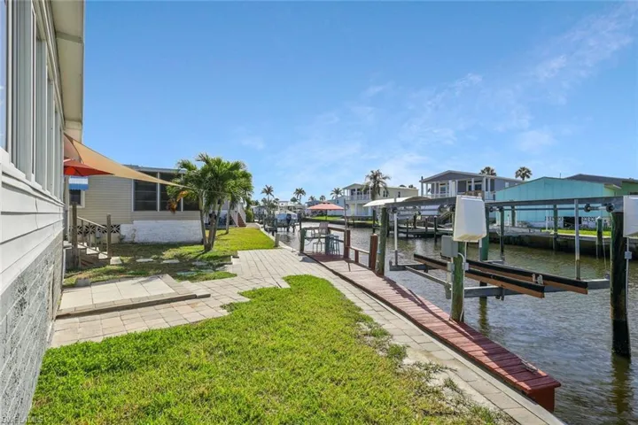 View of dock featuring boat lift, a residential view, a water view, and a lawn