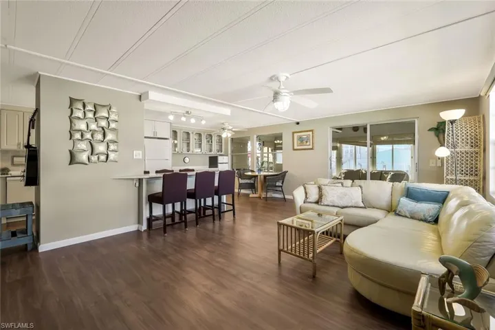 Living room featuring dark wood-type flooring, baseboards, a textured ceiling, and ceiling fan