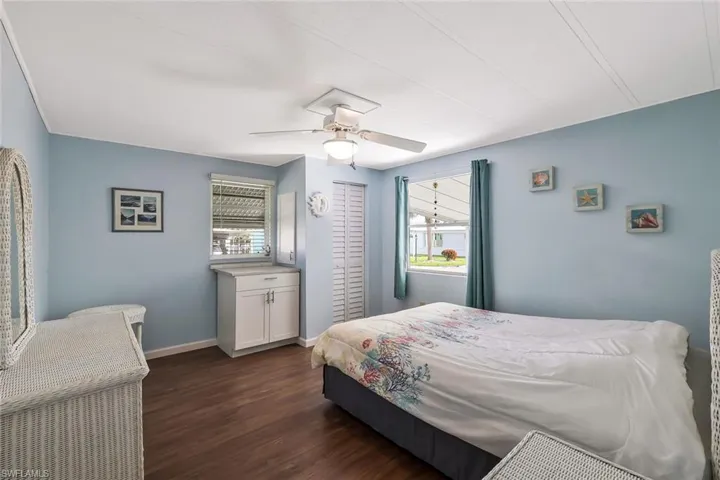 Bedroom with dark wood finished floors, baseboards, and ceiling fan