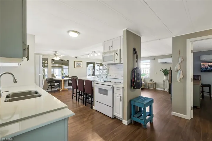 Kitchen featuring white appliances, a wall unit AC, light countertops, and a sink