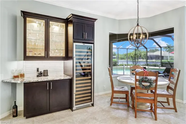 Tiled dining space with ornamental molding, a chandelier, and wine cooler