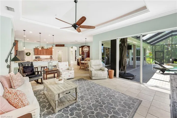 Tiled living room with crown molding, ceiling fan, sink, and a tray ceiling