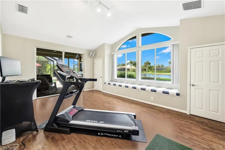 Exercise area featuring lofted ceiling, wood-type flooring, and track lighting