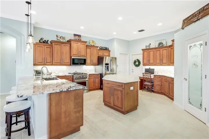 Kitchen with tasteful backsplash, decorative light fixtures, stainless steel appliances, light stone counters, and sink