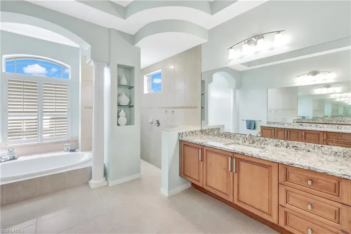 Bathroom with vanity, tile patterned floors, decorative columns, and plus walk in shower