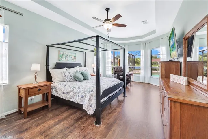 Bedroom featuring a raised ceiling, ceiling fan, and dark hardwood / wood-style floors