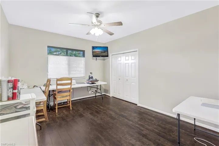Office with dark wood-type flooring and ceiling fan