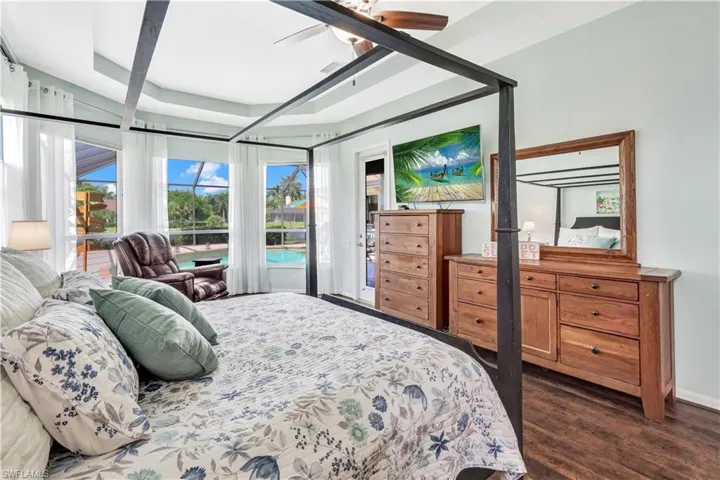 Bedroom with dark wood-type flooring, ceiling fan, and a raised ceiling