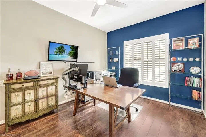 Office space with dark hardwood / wood-style flooring and ceiling fan