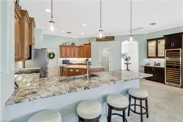 Kitchen featuring pendant lighting, kitchen peninsula, wine cooler, and tasteful backsplash