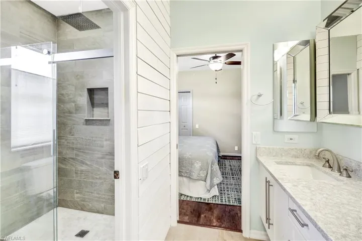 Bathroom featuring tile patterned floors, tiled shower, ceiling fan, and vanity