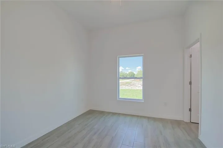 Unfurnished room featuring light wood finished floors and baseboards