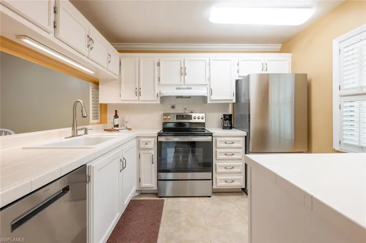 Kitchen with backsplash, white cabinetry, light tile patterned floors, sink, and stainless steel appliances