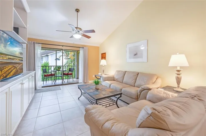 Tiled living room featuring high vaulted ceiling and ceiling fan